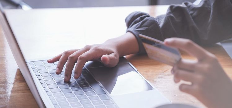 Online Shopping. Asian woman typing credit card information by laptop keyboard for shopping online