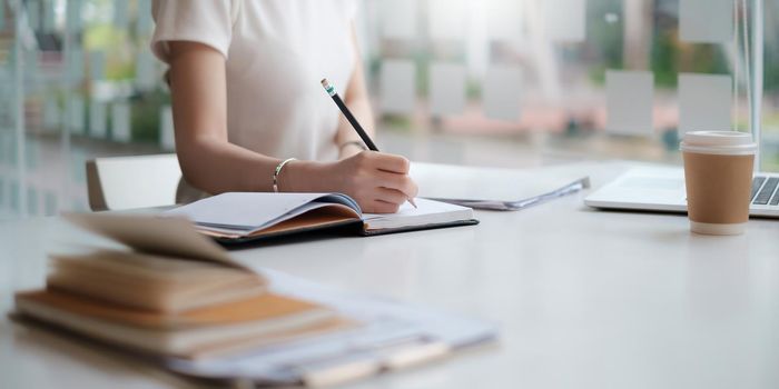 Concept of finance economy, banking business and stock market research. Business accountant or financial holding pencil writing at notebook on desk