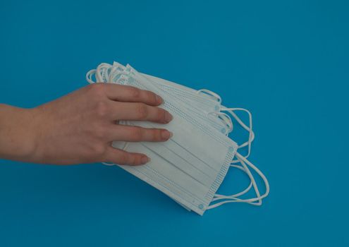 Medical masks in a woman's hand on a blue background. Close-up.