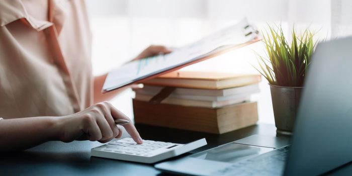 Business woman using calculator for do math finance on wooden desk in office, tax, accounting, statistics home accounring concept