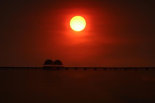sunset back on silhouette bridge and abandon pavillion in the sea