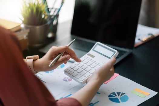 Business woman using calculator for do math finance on wooden desk in office, tax, accounting, statistics home accounring concept