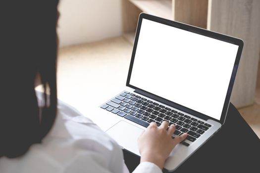 Asian woman using laptop computer mockup and blank screen with morning light at home office