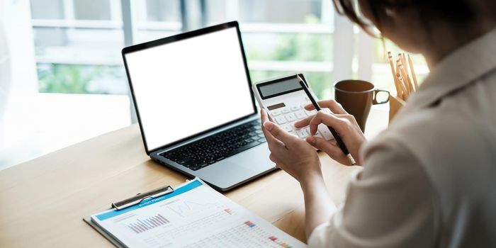 Close up of woman calculating financial or taxes or household on calculator, female calculate while sitting at her home and make payment