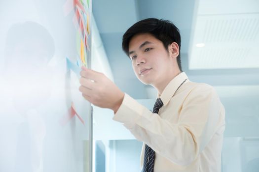 Young creative man picking best ideas on wall full of sticky notes