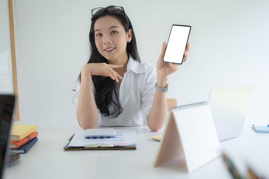 Portrait of Asian Business woman holding smartphone with blank screen working from home. Accounting concept