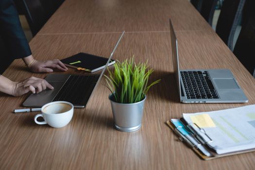 Close up Business woman using laptop for do math finance on wooden desk in office and business working background, tax, accounting concept.