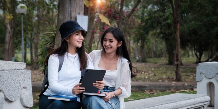 Asian woman traveler with backpack using maps on tablet and sitting in park, travel holiday relaxation concept