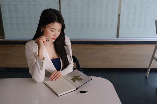 Businesswoman thinking about work with notebook at her office desk