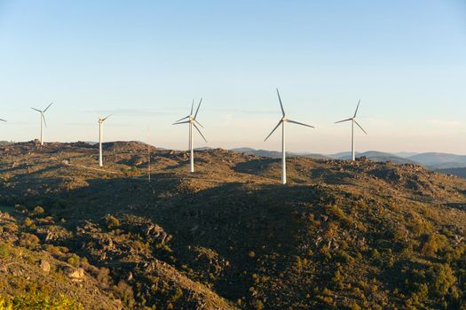 Sortelha nature landscape view with mountains, trees, boulders and wind turbines at sunset, in Portugal