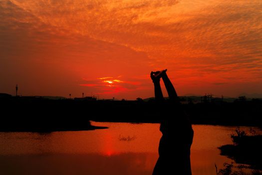 Silhouette of woman exercises riverside at sunset Yellow on sky beautiful in summer