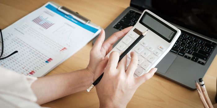 Close up of woman calculating financial or taxes or household on calculator, female calculate while sitting at her home and make payment