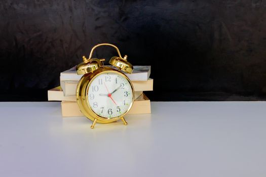 alarm clock old vintage gold and book over white on black background. with copy space add text