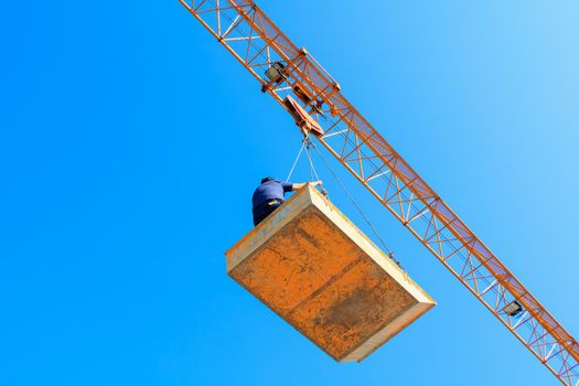 male in bucket of Tower crane. building construction site. blue sky background