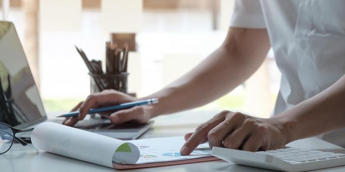 man accountant analyzing financial graph data with calculator.