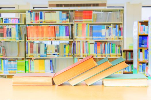 old book red - green. and heap treatise in school library on wooden table.  blurry bookshelves background. education learning concept with copy space add text