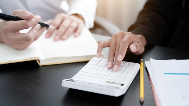 Close up Businessman and partner using calculator and laptop for calaulating finance, tax, accounting, statistics and analytic research concept.