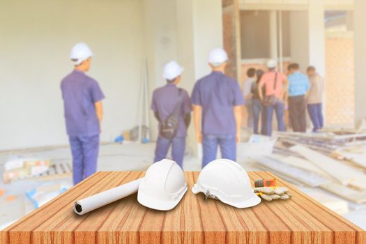 two white safety helmet and leather glove Measuring Tape, roll paper plan blueprint for engineering working interior construction site building on wood floor table with copy space add text. blur background