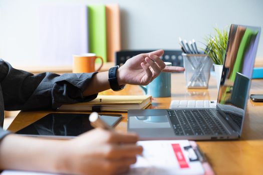 Close up Hand of Businesswoman pointing and analyzing charts by document and laptop computer