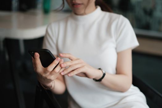 Close up of hand holding, using cell phone for invite her friend meeting at cafe when open after covid-19 have vaccine