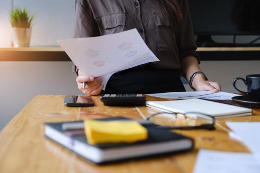 Close up Hand of Businesswoman pointing and analyzing charts by document