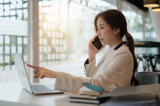 Banker telling to client regarding bank services make recommendations via cell phone while pointing at laptop. colleagues talking, working on project together concept