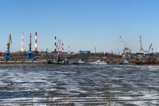Spring ice on the river. Plant by the river and sand mining. High quality photo