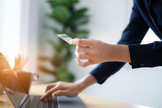 Woman in casual shirt paying with credit card online while making orders via application on tablet. Successful and happy business woman making transaction using mobile bank application