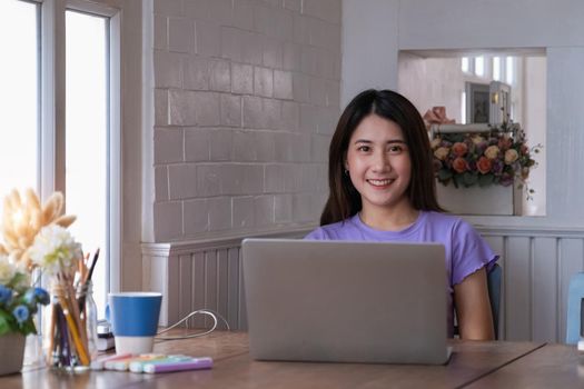 Portrait of beautiful woman and smiling using video call on laptop computer with her parents. Quarantine and work from home concept