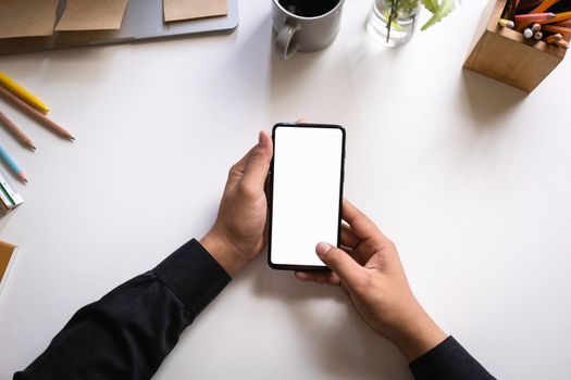Businessman using smartphone with blank screen on wooden desk. work from home concept