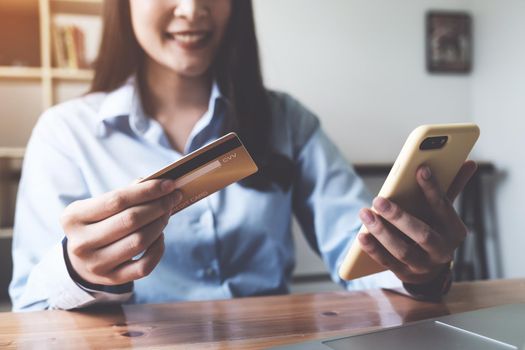 Online payment. Asian woman holding credit card and smartphone for online shopping and payment makes a purchase on the Internet