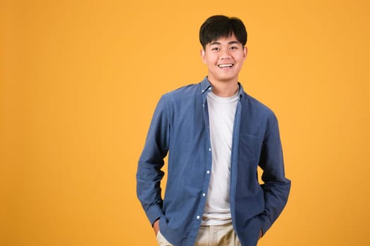 Portrait of a confident handsome young man smiling against yellow background, studio shot. 
