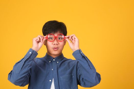 Portrait of asian nerd man with red glasses on yellow background, studio shot.