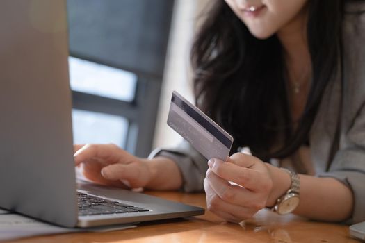 Online Shopping. Asian woman typing credit card information by laptop for shopping online