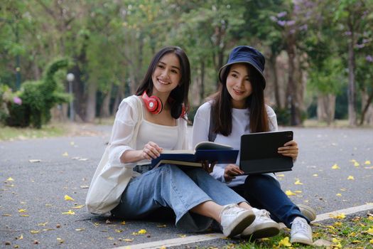 Two students are sitting during reading a book and communication. Study, education, university, college, graduate concept.