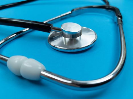 Black stethoscope on a blue background. Stock photo.