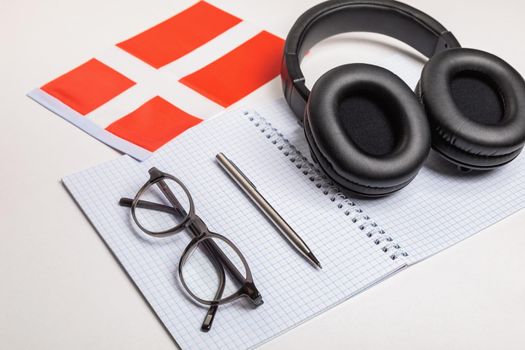Learning foreign languages in Denmark with audio recordings and headphones. Notepad, glasses, pen.