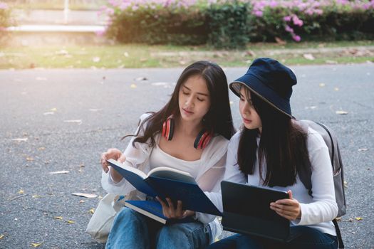 Two students are sitting in university during reading a book and communication. Study, education, university, college, graduate concept