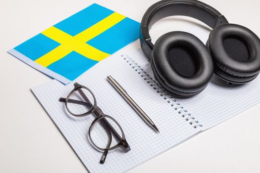 Learning foreign languages in Sweden with audio recordings and headphones. Notepad, glasses, pen.