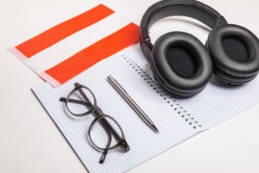 Learning foreign languages in Austria with audio recordings and headphones. Notepad, glasses, pen.