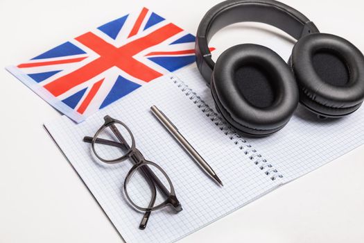Learning foreign languages in the UK with audio recordings and headphones. Notepad, glasses, pen.