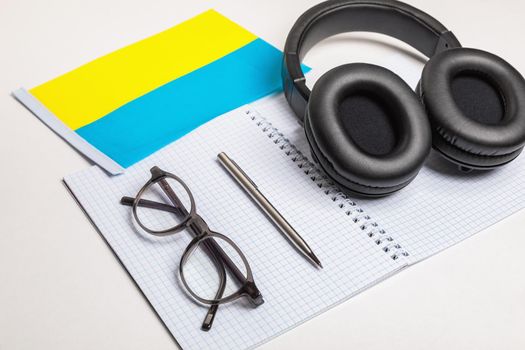 Learning foreign languages in Ukraine with audio recordings and headphones. Notepad, glasses, pen.