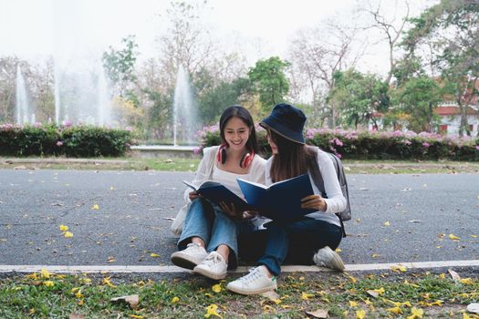 Two students are sitting in university during reading a book and communication. Study, education, university, college, graduate concept