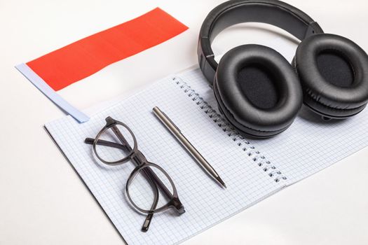 Learning foreign languages in Indonesia with audio recordings and headphones. Notepad, glasses, pen.
