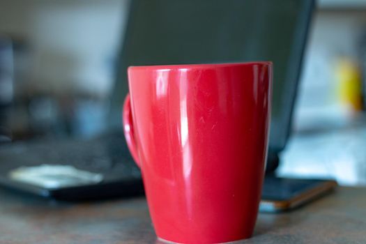 Office workplace with coffee and charts on wooden desk table in front of window with blinds