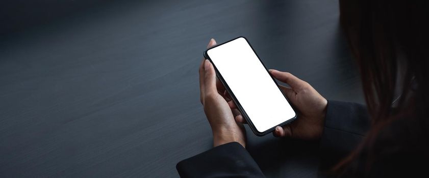 cell phone blank white screen mockup. woman hand holding texting using mobile on desk at office.background empty space for advertise