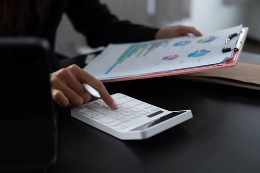 Woman with financial report and calculator. Woman using calculator to calculate report at the table in office.