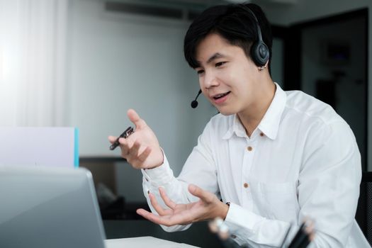 Businessman discuss with partners by video call. Male technical support agent trying to explain something to a client while working on laptop at call center