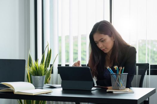 Businesswoman working with a stylus pen on a digital tablet with a laptop computer in a modern office