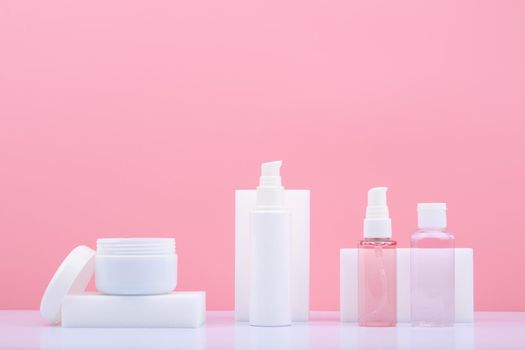 Set of beauty products for skin care in white tubes on white table against bright pink background with copy space. Concept of skin daily, anti aging or anti acne treatment